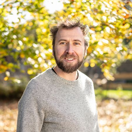 Auf diesem Bild ist der Kollege Arne Jährling in Profilansicht vor einem Herbstbaum zu sehen.