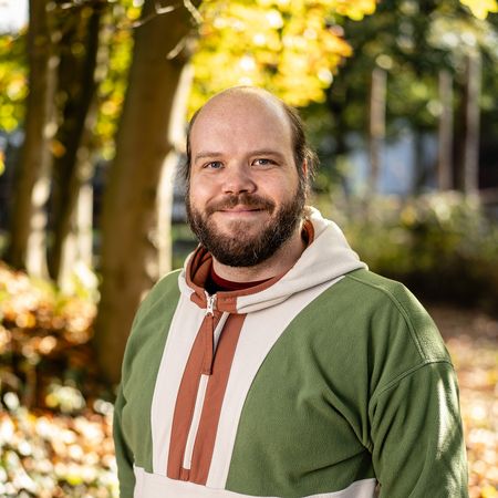 Auf diesem Bild ist der Kollege Michael Rosenbaum in Profilansicht vor einem Herbstbaum zu sehen.