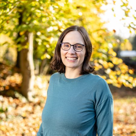 Auf diesem Bild ist die Kollegin Sara van den Broek in Profilansicht vor einem Herbstbaum zu sehen.